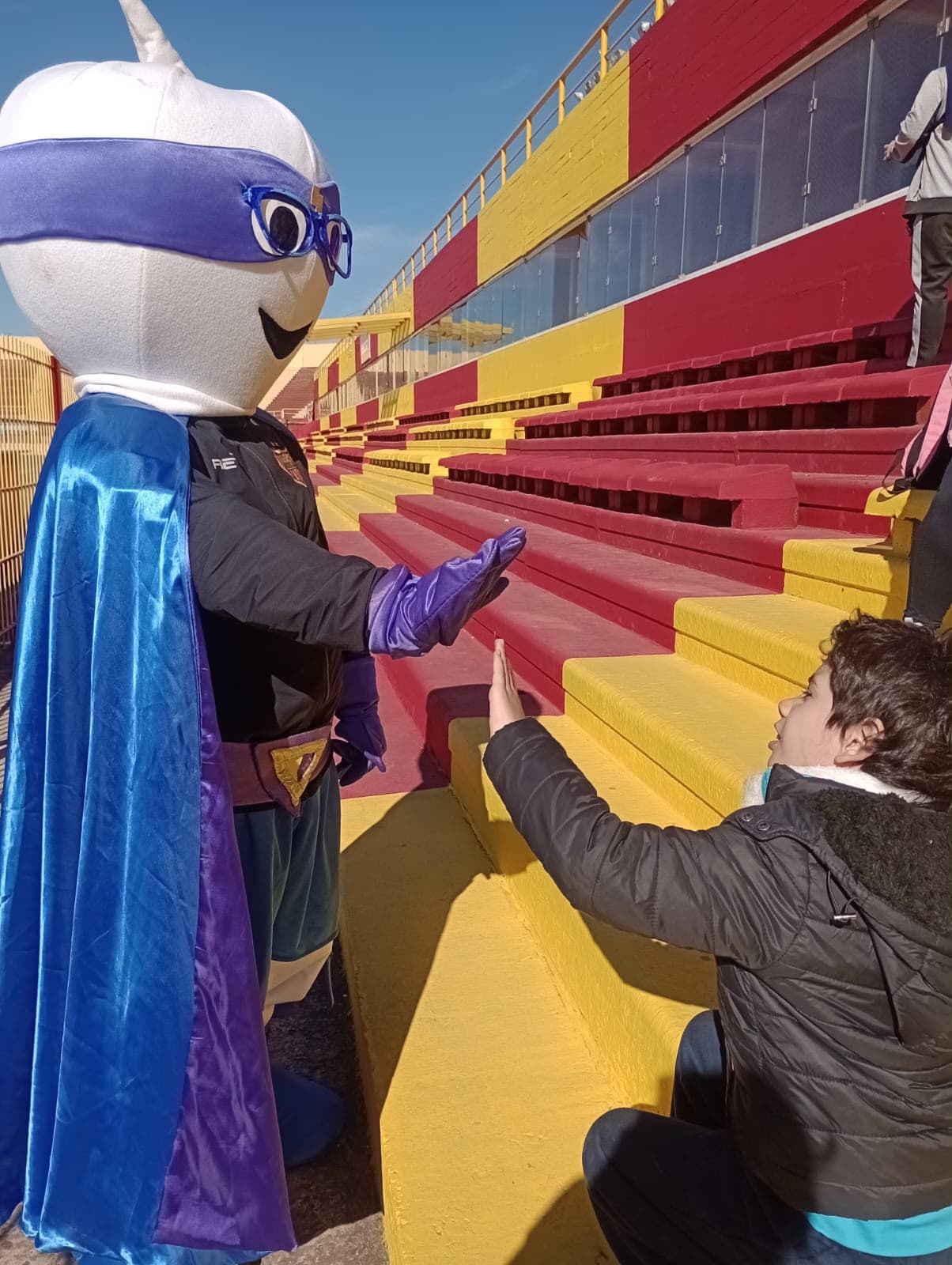 La mascota de Yo Puedo chocando la mano con un niño en una salida