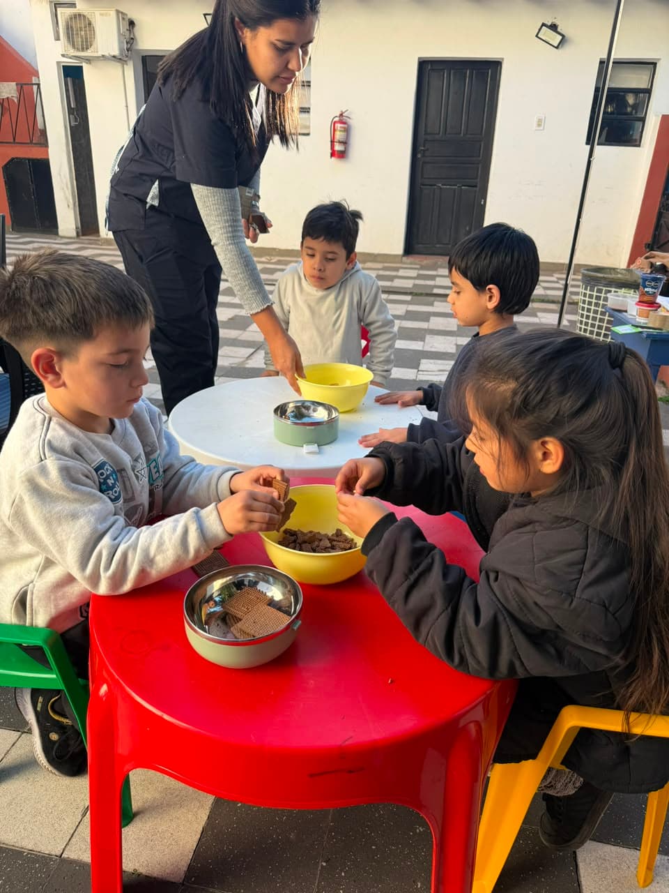 Niños compartiendo una merienda junto a una profesional