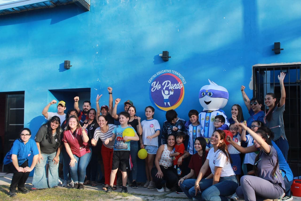 Equipo y familias celebrando frente al mural institucional