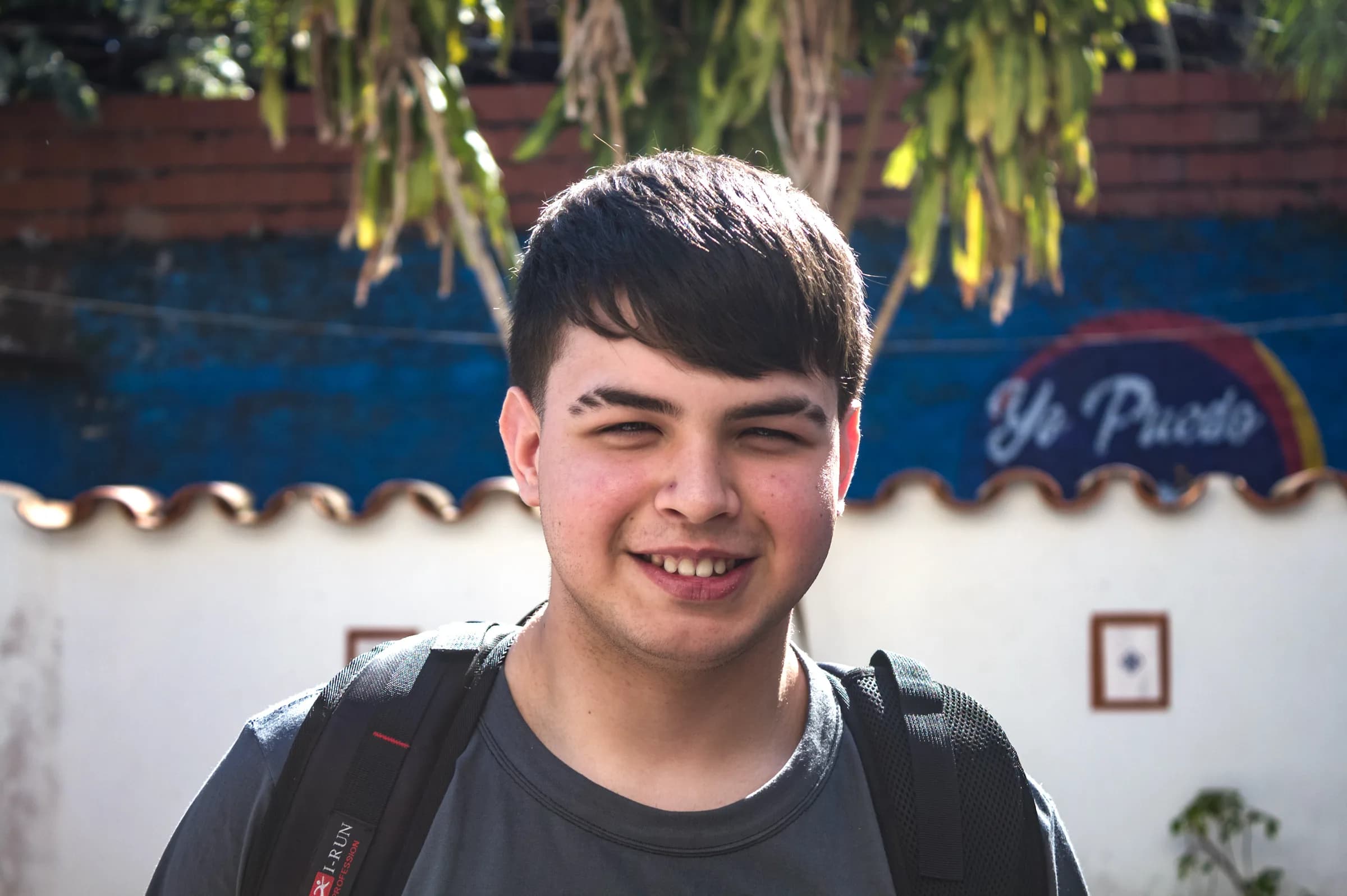 Adolescente sonriendo frente al mural de Yo Puedo
