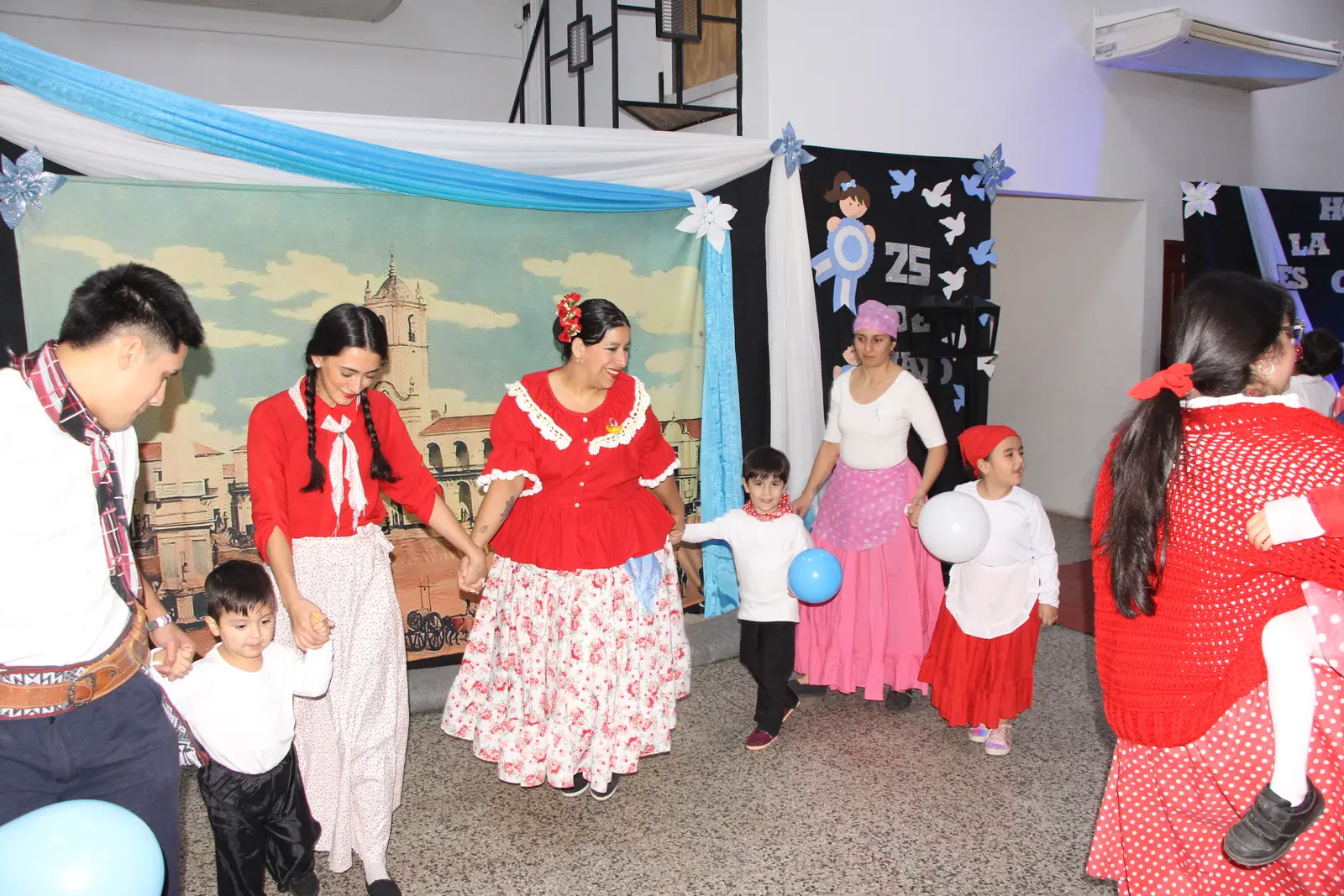 Chicos y adultos bailando folclore en la celebración del 25 de Mayo